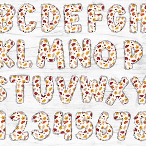 May include: A set of alphabet letters and numbers with a fall leaf pattern. The letters and numbers are white with a black outline and are filled with a pattern of red, orange, and yellow leaves.