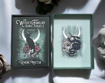 May include: A dark green oracle card box set with the text "The Witch's Familiar Runic Oracle Guidebook" and "Athene Noctua". The box features a black cat, flowers, and a crescent moon design. The open box reveals a matching design with a snake.
