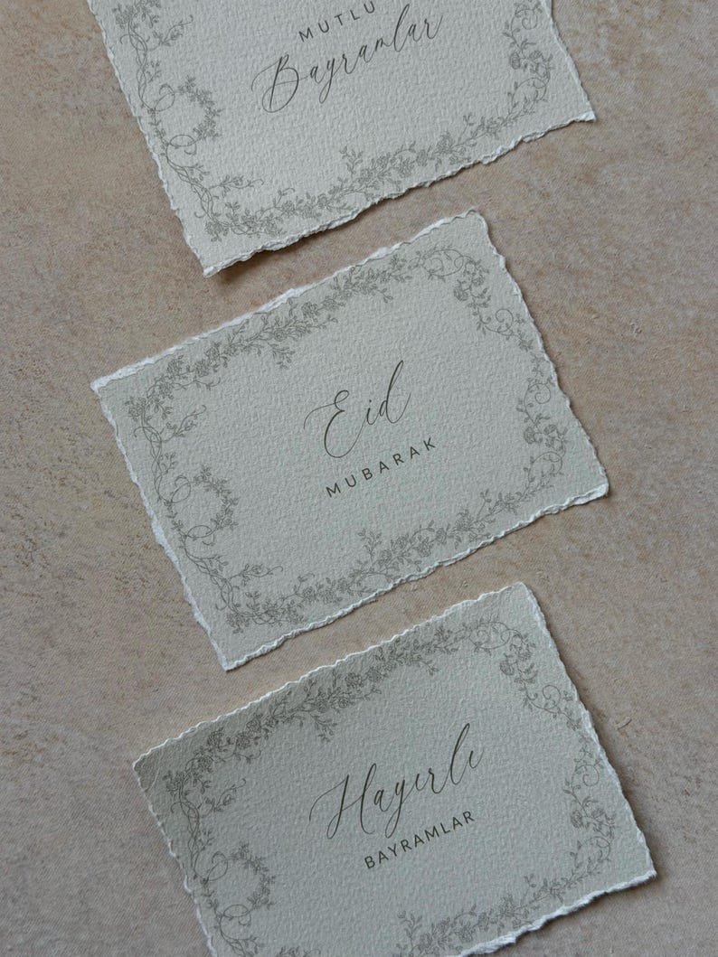 Pu&ograve; includere: Tre cartoline rettangolari con bordi irregolari, caratterizzate da una superficie testurizzata grigio chiaro e un delicato bordo floreale. Le cartoline riportano il testo Mutlu Bayramlar, Eid Mubarak e Hayirli Bayramlar in un mix di caratteri corsivi e sans-serif.