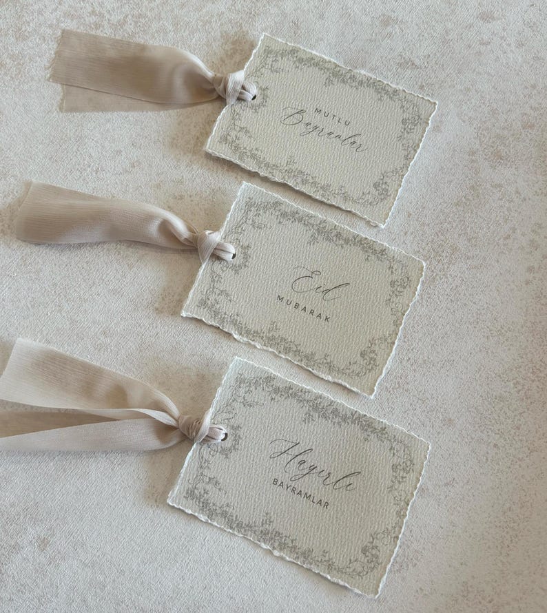 Pu&ograve; includere: Tre etichette regalo beige con bordi strappati e bordi floreali. Ogni etichetta ha un nastro beige attaccato. Le etichette hanno il testo: "Mutlu, Beğenler", "Eid, Mubarak" e "Hayırlı, Bayramlar".