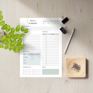 May include: A printable daily planner with sections for top priority, schedule, meal plan, shopping list, and notes. The planner has a simple design with a floral illustration and a light gray background.