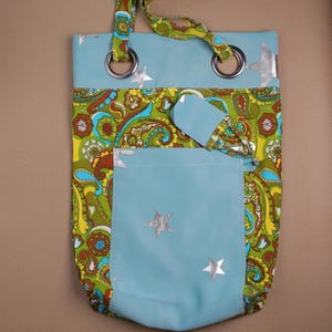 Op de afbeelding: Een blauwe draagtas met een paisley patroon in groen, geel en bruin. De tas heeft een blauw vak met zilveren steraccenten en een bijpassende handgreep. Zilveren ogen bevestigen de handgreep aan de tas.