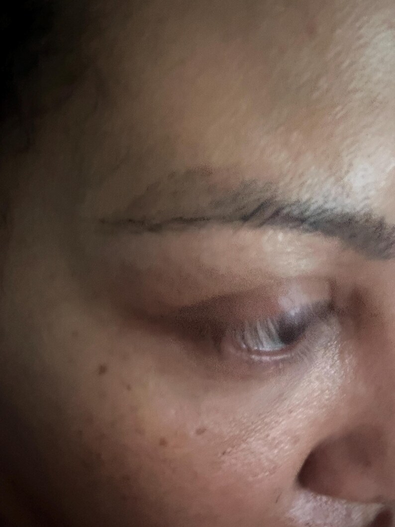 May include: Close-up of a person's face, showing a single eye with dark eyelashes and a defined eyebrow. The skin is light-toned and has a few freckles.