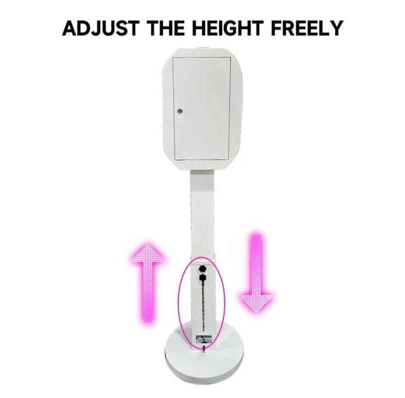 May include: White photo booth stand with a white rectangular box on top. The stand has a telescoping pole that can be adjusted up and down to change the height of the booth. The pole is marked with arrows indicating the direction to adjust the height.