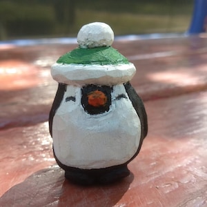 帽子をかぶったペンギン。木製のペンギン。ペンギンの彫刻。ペンギンの像