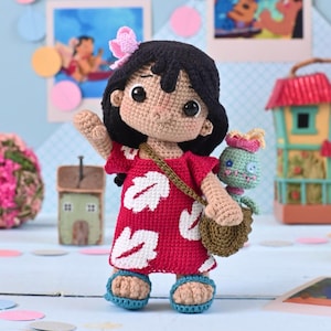 May include: Crocheted doll of a character in a red dress with white leaf designs, black hair, and a pink bow. The doll carries a small brown bag with a green and blue creature inside. Blue sandals complete the look. The background includes miniature houses and colorful decorations.