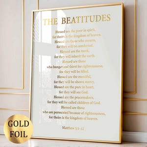 Könnte beinhalten: Gerahmter Druck mit goldenem Text auf cremefarbenem Hintergrund. Der Text lautet "DIE SELIGPREISUNGEN", gefolgt von Versen aus Matthäus 5:1-12. Ein goldener Folienaufkleber befindet sich in der unteren linken Ecke. Der Rahmen ist goldfarben.