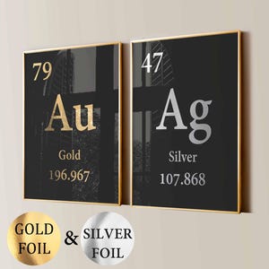 May include: Two framed art prints with gold and silver foil accents. The left print features "Au" for Gold, and the right print features "Ag" for Silver, both on a black background. The prints are in gold frames.