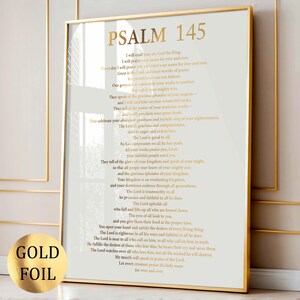 Op de afbeelding: Een verticale wandkunstprint met Psalm 145 in goudfolie letters op een witte achtergrond, ingelijst in een dunne gouden lijst. De tekst toont het volledige bijbelgedeelte in een schreeflettertype, met de titel Psalm 145 bovenaan in grote letters.
