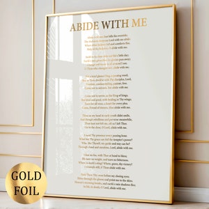 Puede incluir: Impresión enmarcada con el poema "ABIDE WITH ME" en letras doradas sobre fondo blanco. Una pegatina dorada está en la esquina inferior izquierda. El marco dorado añade elegancia.