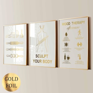 May include: A set of three wall art prints with gold foil details on a white background. The first shows wood therapy tools, the second depicts a human torso with a roller and the text SCULPT YOUR BODY, and the third lists WOOD THERAPY aftercare.
