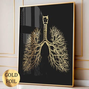Può includere: Una stampa artistica incorniciata con un'illustrazione anatomica in lamina d'oro dei polmoni su sfondo nero. L'opera d'arte è racchiusa in una cornice dorata. Le parole "GOLD FOIL" sono stampate su un adesivo in lamina d'oro.
