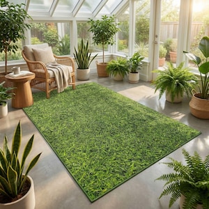 Könnte beinhalten: Ein rechteckiger grüner Teppich mit grasartiger Textur liegt auf einem Betonboden. Der Teppich ist von Topfpflanzen und einem Korbstuhl mit beigem Kissen und Decke umgeben. Der Raum hat große Fenster.