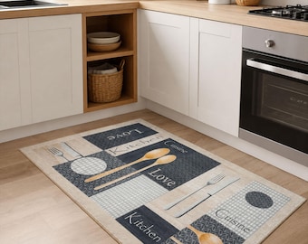 May include: A rectangular kitchen rug with a beige background and navy blue and white geometric patterns. The rug features images of wooden spoons, forks, and knives, along with the words "Kitchen", "Cuisine", and "Love".