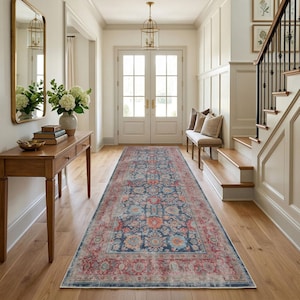 Könnte beinhalten: Ein langer, rechteckiger Teppich mit einem detaillierten Blumenmuster in Marineblau, Rot und Orange. Der Teppich liegt in einem Flur mit Holzböden und einer weißen Wand. Das Design des Teppichs umfasst einen Rand und ein zentrales Medaillon.