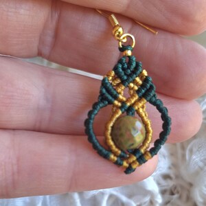 May include: Green and gold macrame earrings with a green and brown stone pendant.