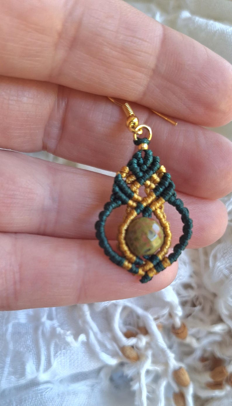 May include: Green and gold macrame earrings with a green and brown stone pendant.