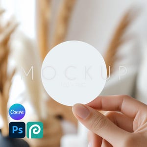May include: A white round sticker mockup held in a hand. The sticker is blank and ready for your design.  The text "MOCKUP PSD + PNG" is visible on the sticker.