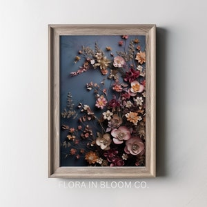 May include: A framed artwork featuring a 3D floral arrangement with a variety of pink, red, and orange flowers on a blue background. The text "FLORA IN BLOOM CO." is printed below the frame.