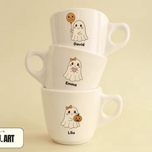 May include: Three white ceramic mugs stacked, each with a different cartoon ghost design. One ghost holds a pumpkin balloon, another a heart, and the last a pumpkin. Each mug has a name: David, Emma, and Lilu.