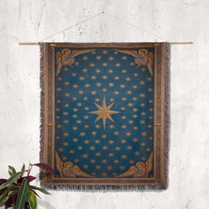 May include: A blue tapestry with a celestial design, featuring numerous gold stars and a central eight-pointed star. The tapestry has a gold border with angel figures at the top and bottom. It is hung on a wooden rod.