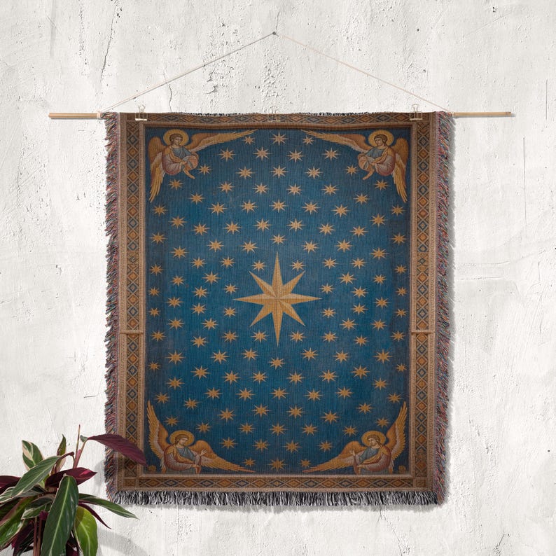 May include: A blue tapestry with a celestial design, featuring numerous gold stars and a central eight-pointed star. The tapestry has a gold border with angel figures at the top and bottom. It is hung on a wooden rod.
