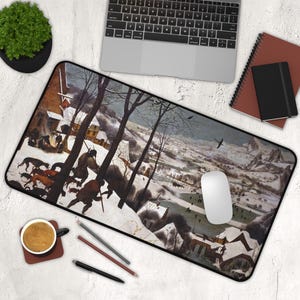 May include: A rectangular mousepad featuring a winter landscape painting with figures, dogs, and buildings. The artwork is predominantly white, brown, and black, with a black border. A laptop, mouse, and other office supplies are also visible.