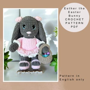 Puede incluir: Un conejito de Pascua de crochet gris que lleva un vestido rosa y sostiene una cesta de huevos de colores. El conejito está de pie sobre una superficie de madera con una planta verde en el fondo. El texto "Esther the Easter Bunny CROCHET PATTERN PDF" está escrito en blanco sobre un círculo con fondo gris. El texto "Pattern in English only" está escrito en negro sobre un fondo blanco.