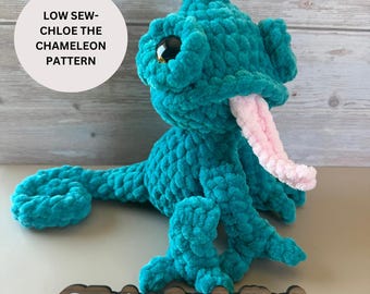 May include: A teal blue crocheted chameleon with a pink tongue. The chameleon is sitting on a wooden surface with the text "@TashasCrochetNook" written on it. The text "LOW SEW-CHLOE THE CHAMELEON PATTERN" is written on a white circle in the top left corner of the image.
