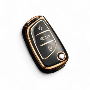 May include: A black car key fob with a gold trim. The key fob has three buttons: unlock, lock, and trunk release.