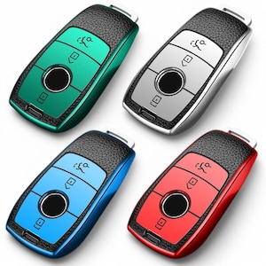 May include: Four key fobs in different colors: green, silver, blue, and red. Each fob has a black leather-like texture and features a keyhole icon, a button with a downward arrow, and a round button with a small square inside.