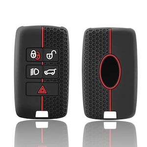 May include: Two black car key fobs with red detailing. One shows lock, unlock, headlight, and boot release symbols. The other has a honeycomb design and a red oval. Both have a white rectangular base.