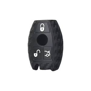 May include: Black carbon fiber key fob cover with four buttons. The cover has a textured surface and a black finish.