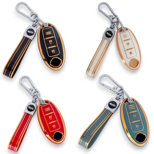 Puede incluir: Cuatro llaveros de coche en negro, crema, rojo y verde azulado. Cada llavero tiene una correa a juego y un borde dorado metálico alrededor del llavero. Los llaveros tienen un logotipo de coche y símbolos de llave.