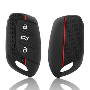Puede incluir: Dos fundas negras para llaves de coche con rayas rojas. Una funda tiene un patrón de panal y iconos blancos para bloquear, desbloquear y abrir el maletero. La otra funda tiene una superficie lisa con una raya roja.