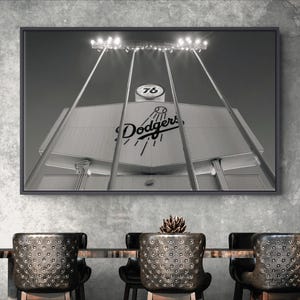 May include: A black and white framed wall art print depicting the Los Angeles Dodgers stadium scoreboard and iconic 76 ball sign. The image features the Dodgers logo, a baseball graphic, and bright stadium floodlights against a dark sky.
