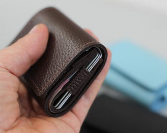 Peut inclure: Un portefeuille en cuir marron avec une fermeture à rabat. Le portefeuille est plié en deux et tenu dans une main.