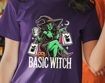 May include: A woman wearing a purple t-shirt with a graphic of a witch holding shopping bags and a coffee cup. The text on the shirt reads "Basic Witch".