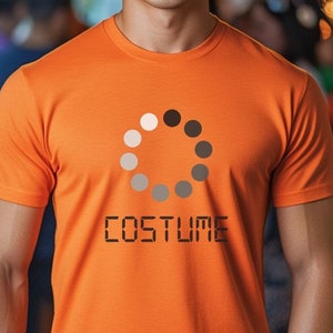 May include: An orange t-shirt with a circular graphic of dots in shades of gray and black, and the word "COSTUME" in digital font. The shirt is worn by a person.