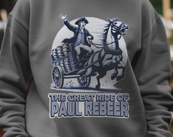 Puede incluir: Una sudadera gris con un gráfico de un hombre montando un caballo que tira de un carro lleno de barriles. El texto "THE GREAT RIDE OF PAUL REBEER" está impreso debajo del gráfico.