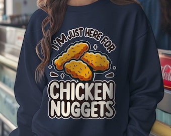 Può includere: Una felpa blu navy con il testo "I'm just here for chicken nuggets" in bianco e una grafica di nuggets di pollo.