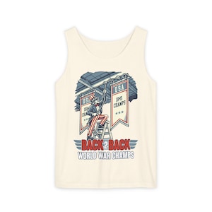 May include: Cream vest top with a graphic of Uncle Sam on a ladder, hanging banners that read "USA 1945 Champs" and "USA 1918 Champs." The text "BACK 2 BACK WORLD WAR CHAMPS" is below the graphic.