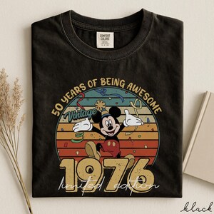 May include: Black t-shirt with a vintage Mickey Mouse design celebrating 50 years of being awesome. The graphic includes Mickey, the year 1976, and the words "limited edition". The shirt is a Comfort Colors brand.
