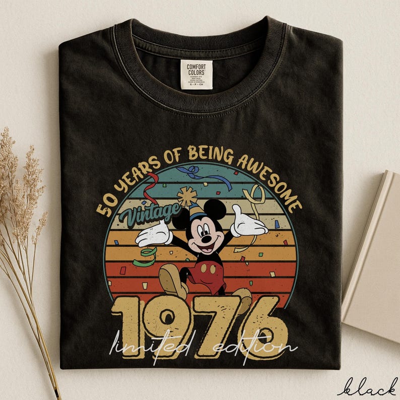 May include: Black t-shirt with a vintage Mickey Mouse design celebrating 50 years of being awesome. The graphic includes Mickey, the year 1976, and the words "limited edition". The shirt is a Comfort Colors brand.
