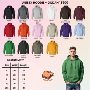 Puede incluir: Exhibici&oacute;n de sudaderas con capucha unisex Gildan 18500 en varios colores, como negro, gris, rojo, naranja y verde. Una tabla de tallas muestra las medidas en cm. Una persona modela una sudadera verde.