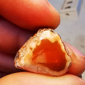 以下が含まれることがあります： 赤、白、茶色の瑪瑙の石のクローズアップ。表面は滑らかで磨かれています。