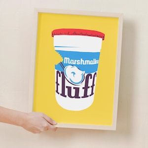 Puede incluir: Una impresión enmarcada de un fondo amarillo con un tarro blanco de crema de malvavisco. El tarro tiene una tapa roja y una etiqueta azul que dice "Marshmallow Fluff". La palabra "fluff" está en fuente morada.