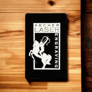May include: Black and white logo on a black background. The logo features a silhouette of a person riding a horse with a bow and arrow. The text "ARCHER LASER ENGRAVING" is written vertically on the right side of the logo.