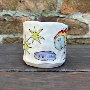 Puede incluir: Taza de cerámica blanca con un diseño pintado a mano de estrellas, un cometa y la palabra "starlight".