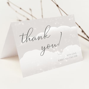 Może przedstawiać: Biała kartka z podziękowaniem z szarym tłem i wzorem białych chmur. Tekst "thank you!" jest napisany czarnym, ozdobnym pismem. Tekst "with love, Amelia + Jacob" jest napisany czarnym kolorem u dołu kartki.